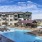 Outdoor swimming pool at Larkspur at Creekside apartments in New Braunfels, TX, featuring lounge chairs and umbrellas.